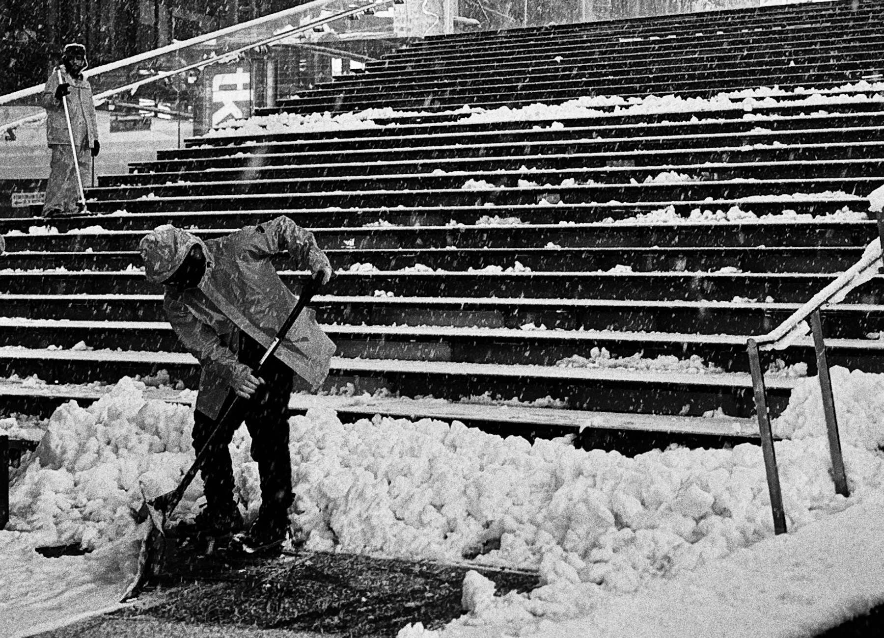 Ein Mann räumt mit einem Schneeschieber eine verschneite Außentreppe